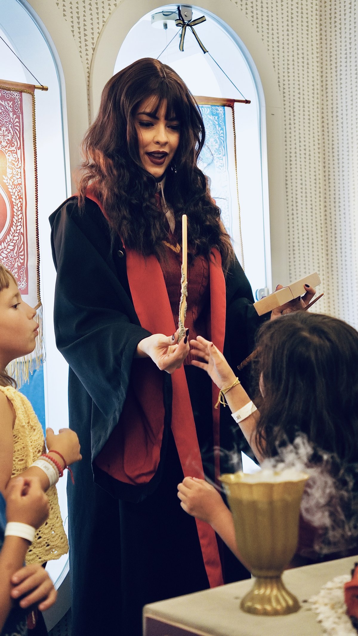 Maju, caracterizada de bruxa de Hogwarts, entrega uma varinha mágica ao Gael durante a festa temática de Harry Potter